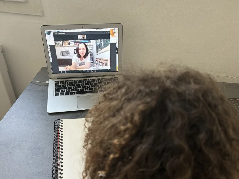 Élève suivant un cours de dessin en visio avec un carnet ouvert